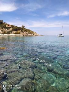 a boat in the water next to a small island at Casa Gaia a soli 20 mt dal mare in Pomonte
