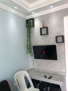 a room with a desk with a tv on a wall at Onde o verão nunca termina! in Peruíbe