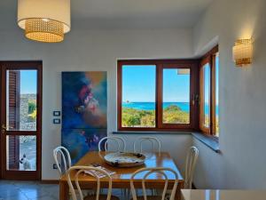 a dining room with a table and chairs and windows at Villa Gino in Stintino +67 photos