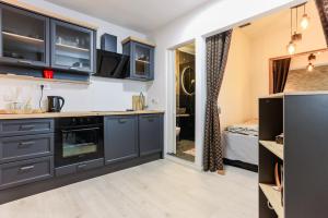 a kitchen with black cabinets and a room with a bed at Boutique Suite 02 Chic in Zadar