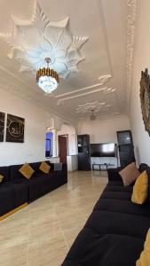 a living room with black couches and a ceiling at Maison campagne piscine ksar in Ksar es Sghir
