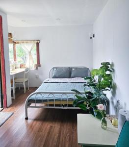 a bedroom with a bed and a table with a plant at Hiên nhà Đà Lạt in Ấp Kim Thạch