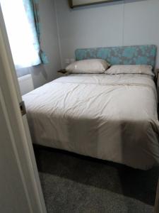 a bedroom with a large bed with a blue headboard at Nutmeg golden sands haven in Mablethorpe +3 photos