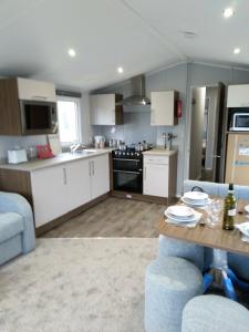 a kitchen with white cabinets and a table and chairs at Nutmeg golden sands haven in Mablethorpe