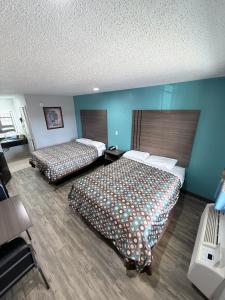 two beds in a hotel room with blue walls at Relax Inn Bryan College Station in Bryan