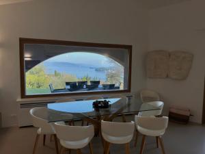 a dining room with a table and chairs and a large window at Villa Allegra Luxury Holiday House in Salò