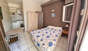 a small bedroom with a bed and a kitchen at Hotel Les Manguiers Jardin de l'Etat Centre Ville Parking Gratuit Canal Sat in Saint-Denis