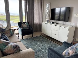 a living room with a tv and a couch and chairs at Durban Point Waterfront, 304 The Quays in Durban