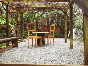 two chairs and a table under a wooden structure at Casa del Estero in Pucón