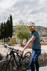 a man standing next to a bike on a road at Cuevas El Atochal Orígenes in Gor