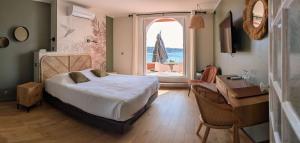a bedroom with a bed and a desk and a window at Les Galets Hôtel et B&B in Bandol