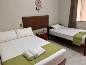 two beds in a hotel room with towels on them at HospedajesPerú in Zorritos