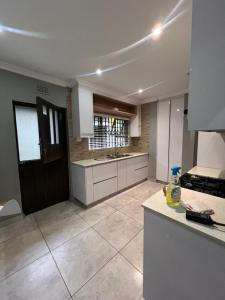 a kitchen with white cabinets and a tile floor at Smith House in Durban