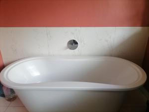 a white bath tub in a bathroom with a red wall at Smith House in Durban