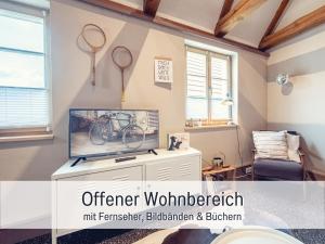 a living room with a tv and tennis rackets on the wall at Molly Moll - Mini Ferienhaus in Kyritz, einer charmanten Stadt im Herzen von Brandenburg in Kyritz