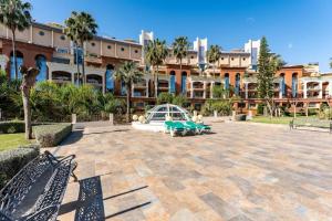 a courtyard with benches and a building with palm trees at BHost - Bellagio II in Benalmádena