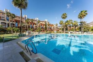 a large swimming pool with palm trees and buildings at BHost - Bellagio II in Benalmádena