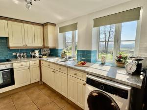 a kitchen with white cabinets and a dishwasher at Blackmoor View Cottage in Sherborne