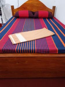 a wooden bed with a remote control on it at Ruwanthera Eco Resort in Ruwanwella