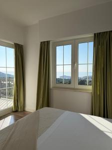 a bedroom with a bed and two windows at Apartment STAR Blažev in Primošten
