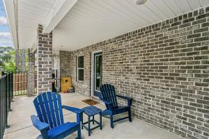 two blue chairs sitting on a porch with a brick wall at Lil Breezy in Navarre