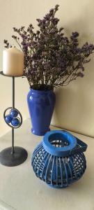 a blue vase with flowers and a candle on a table at Casa da Avó Isaura - Ericeira in Ericeira