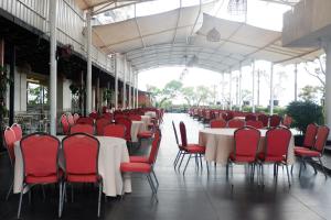 a dining hall with tables and red chairs at The Rich Jogja Hotel in Yogyakarta