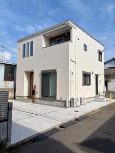 a white brick building on the side of a street at 新築一棟貸切 民宿 夢 駐車場2台無料 コンビニ徒歩2分 市街地へ好アクセス in Matsuyama