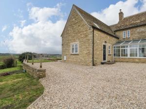 an external view of a stone house with a gravel driveway at Stanbridge Cottage in Malmesbury