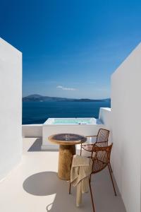 a table and chairs on a balcony with a view of the ocean at You and Me Suites Oia in Oia