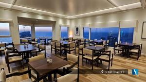 a restaurant with tables and chairs and a view of the ocean at Torres de Manantiales Apart Hotel in Mar del Plata