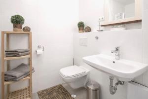 a white bathroom with a sink and a toilet at DUENENROSE App Nr 03 max 3 Pers in Dierhagen