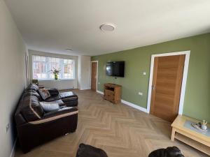 a living room with a couch and a television at 2 Bedroom Bungalow by the Arches in Earlestown