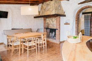 a dining room with a table and chairs and a fireplace at Cuevas El Atochal Orígenes in Gor