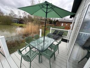 a patio with a table and chairs and an umbrella at Luxury Lakeside Lodge L2 with Hot tub situated at Tattershall Lakes Country Park in Tattershall