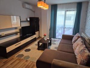 a living room with a couch and a flat screen tv at Stefania Apartment Sibiu in Şelimbăr