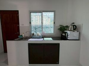a kitchen with a counter with a sink and a window at AN Airport Guesthouse in Nai Yang Beach +7 photos