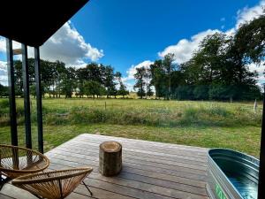 a deck with chairs and a view of a field at Le Vert d'Orezza in Valliquerville