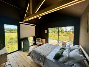 a bedroom with a large bed and a large window at Le Vert d'Orezza in Valliquerville