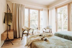 a bedroom with a bed and chairs and windows at Valle Benedetta Retreat Center in Livorno