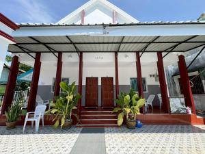 a house with red columns and a porch with chairs at AN Airport Guesthouse in Nai Yang Beach