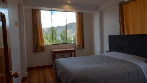 a bedroom with a bed and a large window at Depa Urubamba in Urubamba