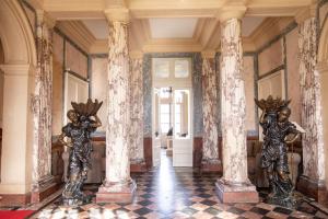 two metal statues in a hallway with columns at Chateau Du Landin in Le Landin