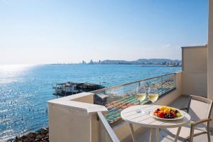 a balcony with a table with a bowl of fruit and wine glasses at Fluctus Apartments in Durrës