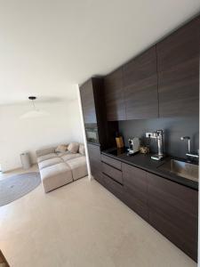 a kitchen with brown cabinets and a couch in it at Villa Čapula - Modern Apartment with Sea View and Parking, Marušići in Omiš