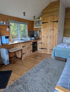 a kitchen with wooden cabinets and a bed in a room at Dryw bach glamping hut in Llandeilo +14 photos