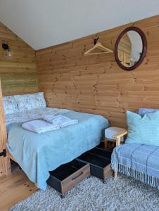 a bedroom with a bed and a mirror at Dryw bach glamping hut in Llandeilo
