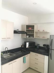 a kitchen with white cabinets and black counter tops at Ph and apartments riviera Maya in Playa del Carmen