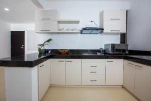 a kitchen with white cabinets and a black counter top at Ph and apartments riviera Maya in Playa del Carmen