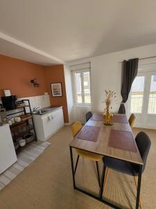 a living room with a table and chairs and a kitchen at Flor du Mont Gîte in Pontorson